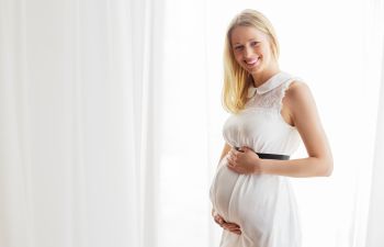 Pregnant blonde woman in white dress.